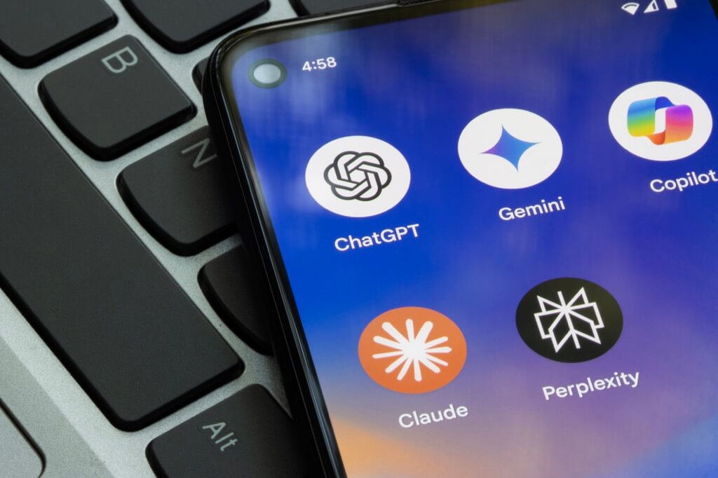 AI Search Optimization Tools on Smartphone Screen Smartphone screen displaying icons for ChatGPT, Gemini, Copilot, Claude, and Perplexity next to a laptop keyboard. Get AI Search Optimization services.